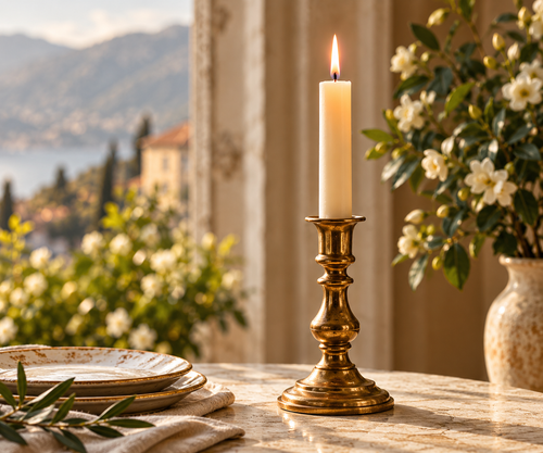 A brass candle holder, set on a marble table with a blurred scenic window background showing mountains and water.